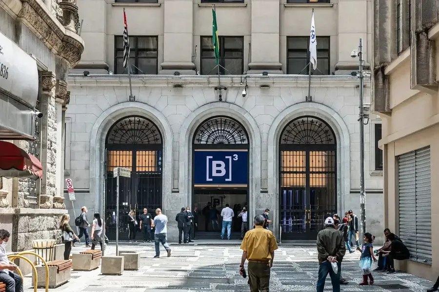 Fachada da B3 no centro de São Paulo, com pessoas passando na calçada.