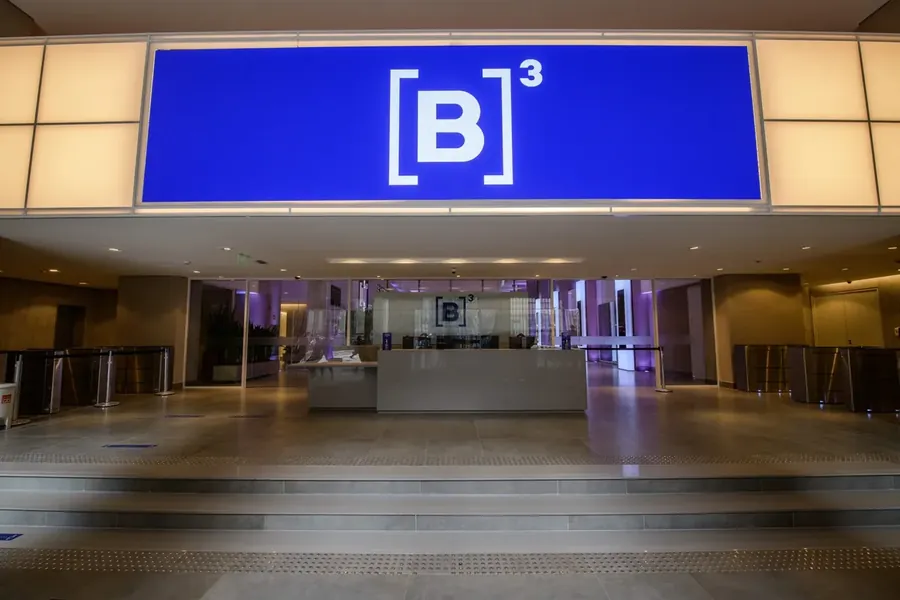Saguão da B3 com o painel azul da marca iluminado ao fundo.